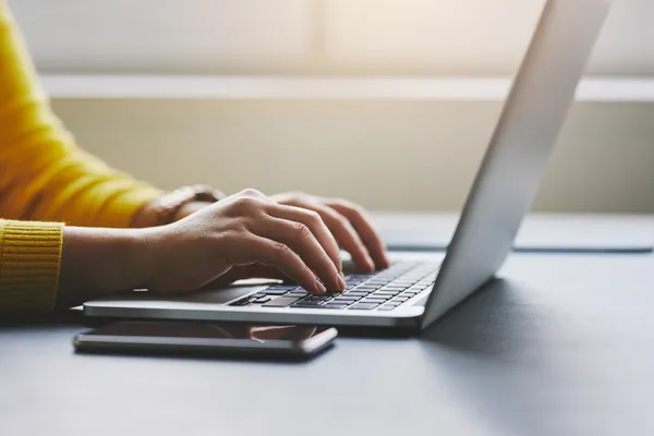 Close up photo of female hands typing on laptop
