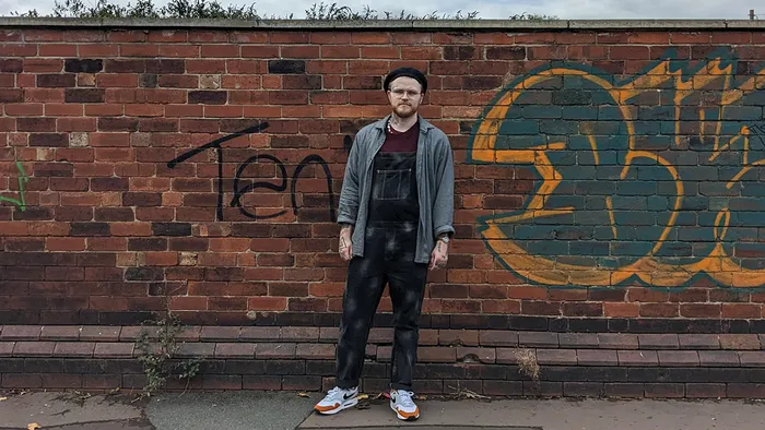 A student posing in front of a brick wall.