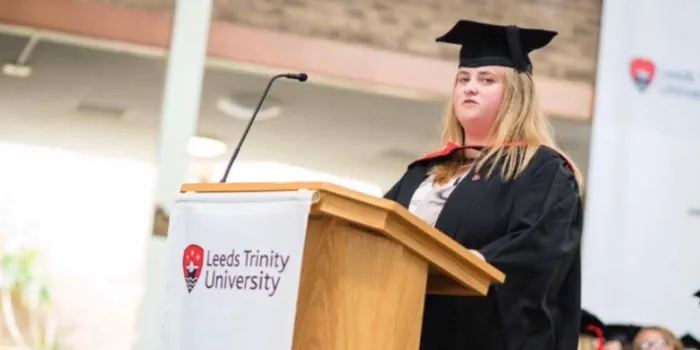 Blonde female student delivers speech in graduation cap and gown