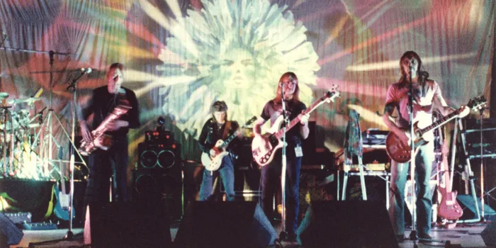 Four men on stage with guitars and microphones