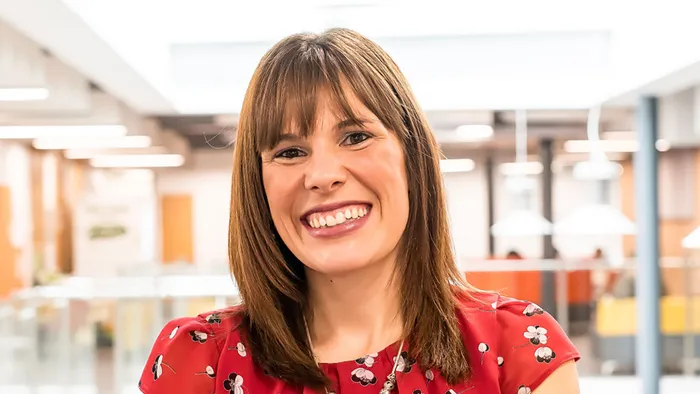 A female academic in a red dress smiling widely.