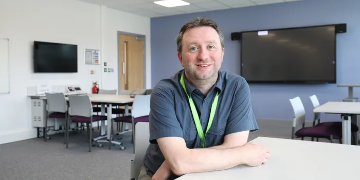 Lecturer sat at desk in teaching room
