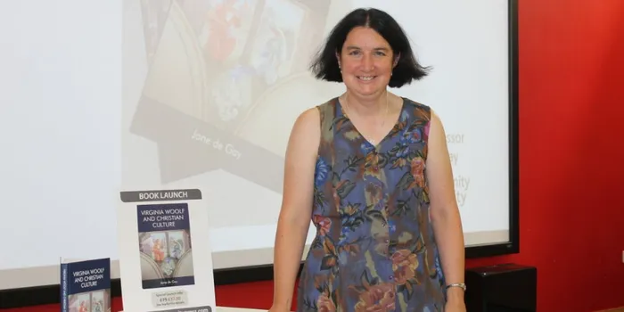 Female lecturer with short dark hair stands in front of screen