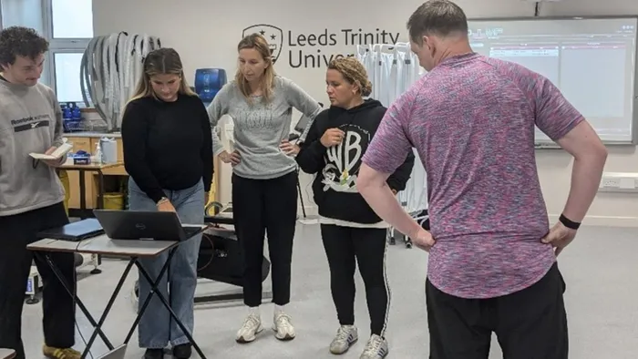 A group of students gather to look at a laptop screen