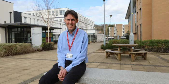 A man sat on a bench outside university building