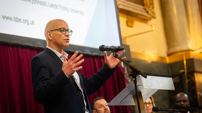 A male academic presenting at a conference.
