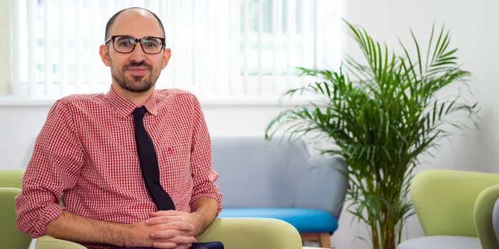 Man with glasses sits on green chair