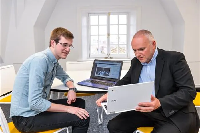 Two men looking at a laptop in an office