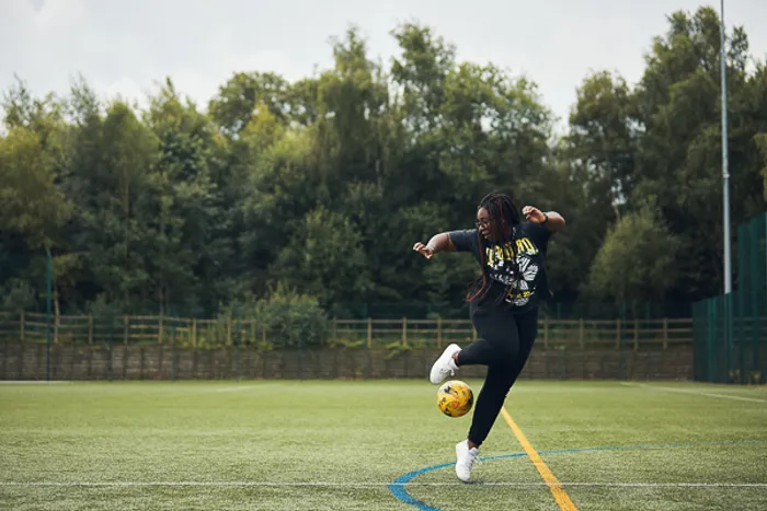 Female student performing a trick with a football on a 3G pitch.