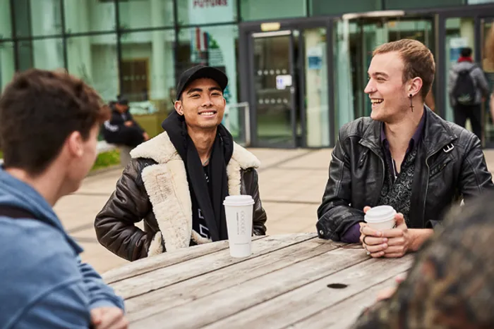 Students drinking coffee outside Main Campus entrance