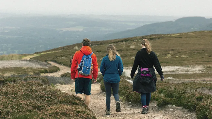 Three people walking on a moor.
