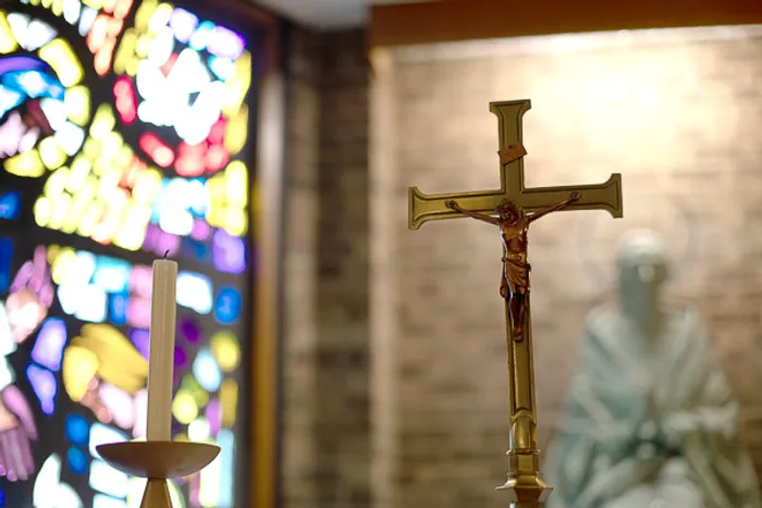 Wooden cross with a stained glass window in the background