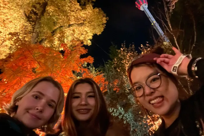 Ella Mather, left, on exchange in Gothenburg Sweden, stood with two others in front of theme park ride in wooded area.