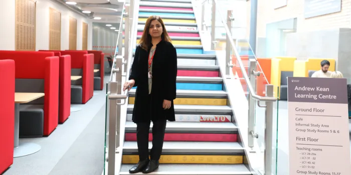 Trainee standing on steps in university library
