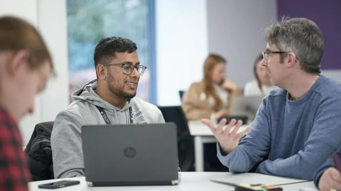 A student sat at a desk listens to an academic