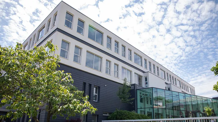 The Leeds Trinity University Main Reception building at the Main Campus in Horsforth, seen from a low angle. It is a grey and white building with a glass front entrance.