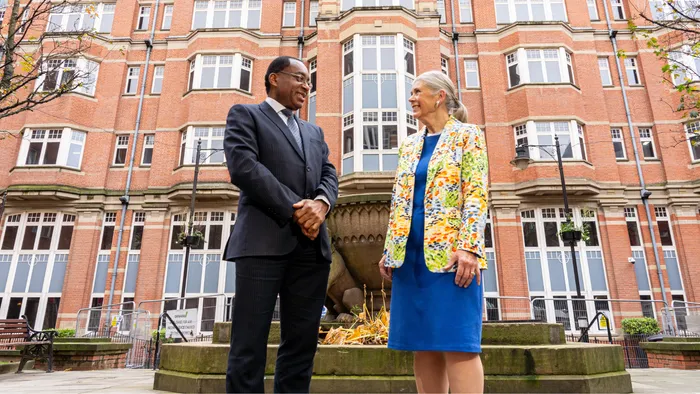 Man and woman, Professor Charles Egbu and Sandi Rhys Jones OBE outside the Leeds Trinity University city centre campus building