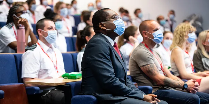 Side view of students in lecture theatre with face masks on, Leeds Trinity Vice Chancellor Charles Egbu sits in the foreground