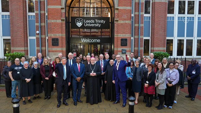 A group of guests with the Bishop of Leeds in front of the Leeds Trinity University City Campus.