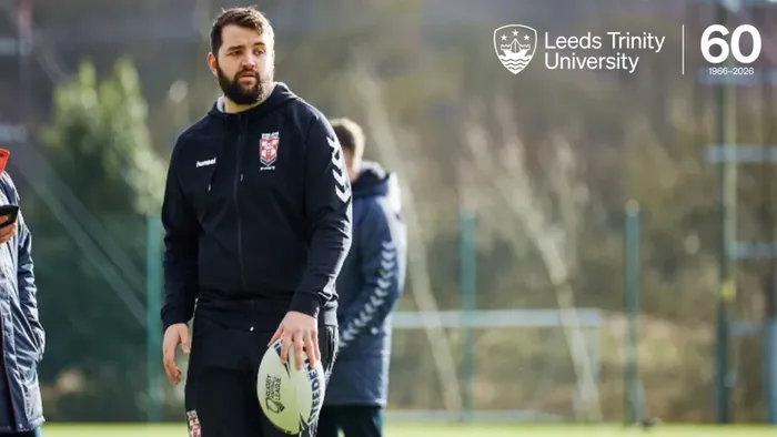 Alumnus Conor Meese stood on a rugby field holding a rugby ball