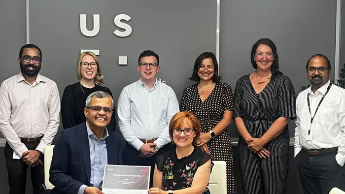 eight people from two businesses (UST and Leeds Trinity University) meet to sign employer agreement.