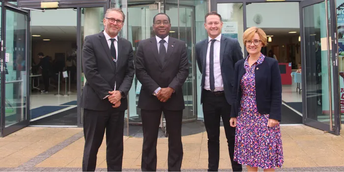 A group of three men and a woman stand outside in front of Leeds Trinity atrium area