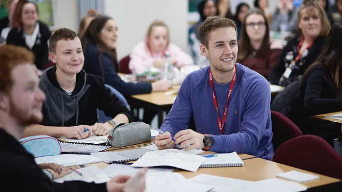 A group of students around a desk with papers and books in front of them.