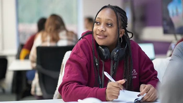 A student in a burgundy hoodie paying attention in classroom.