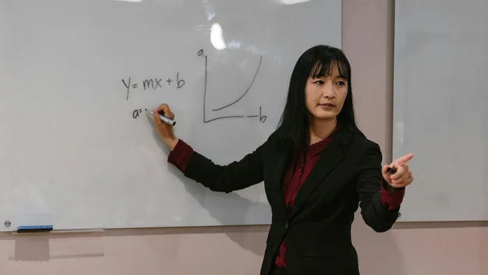A teacher writing maths formulas on a whiteboard.