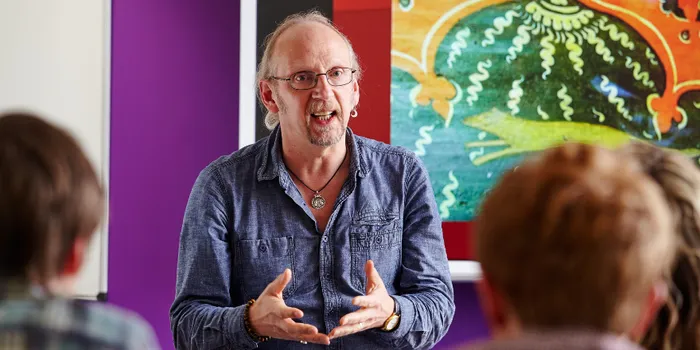 Male lecturer stands in front of students teaching