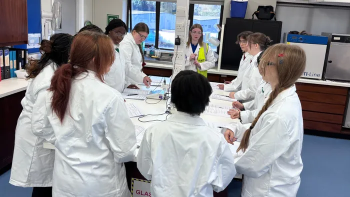 A group of female secondary school students in lab coats at the BASF Bradford site for a day of science activities.