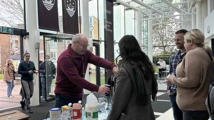 A man stood behind a desk makes a drink for a Tea on the Landing attende