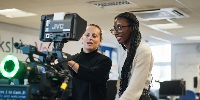 Two female journalism students setting up a camera and autocue