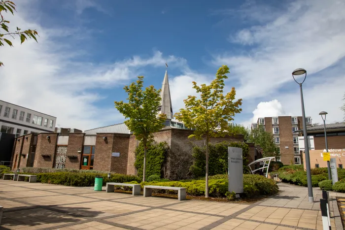 Exterior shot of Leeds Trinity University Chapel on its campus in Horsforth, with green trees and signage in the forefront