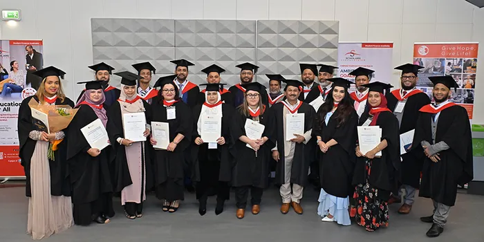 A group of students in caps and gowns holding their degrees.