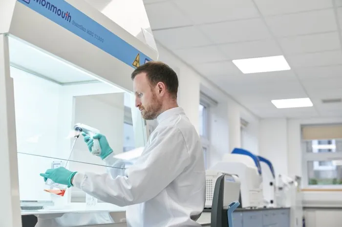 Image of Working in a class II safety cabinet performing cell passage.