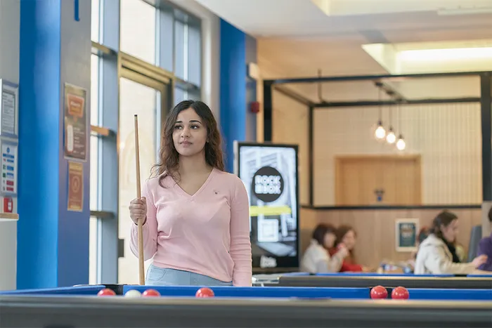 Student in pink top playing pool at LTSU Trini-tea Central.