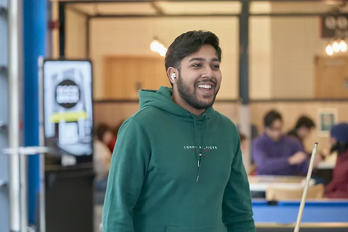 Student in green hoodie playing pool at LTSU Trini-tea Central.