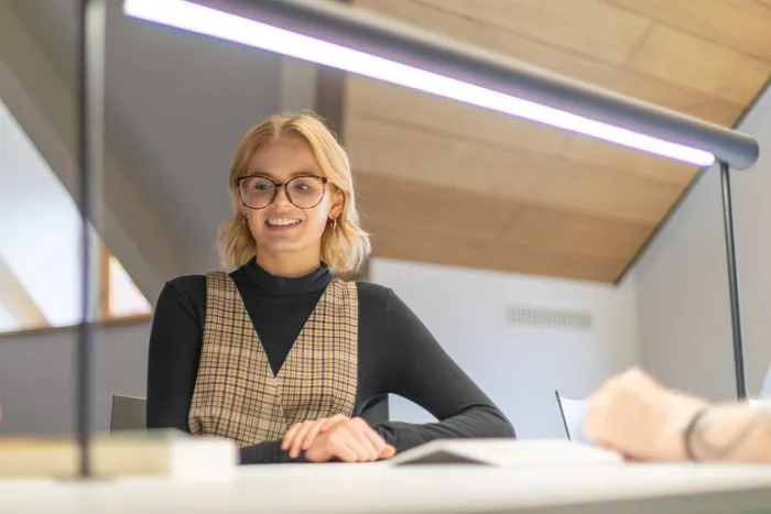 Student looking down at books on a table in a Leeds City Campus social space.