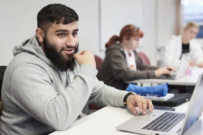 Student using laptop in classroom.