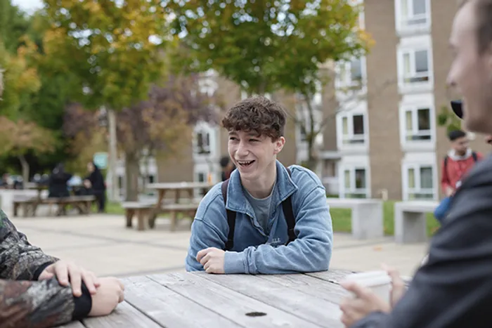 Student sits outside Main Campus on benches