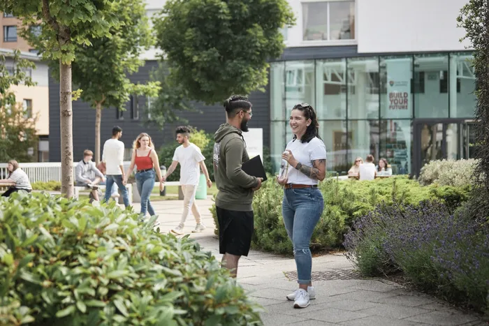 Students talking outside AKLC and Main Campus Reception entrances.