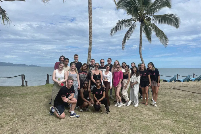 Group photograph of students on a study abroad trip with sea and trees in the background.