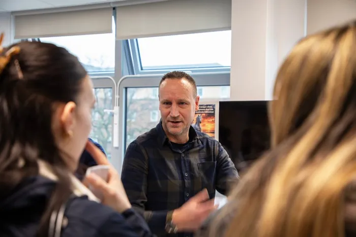Image of Level 5 Psychology students at the Options Fair talking to an academic.